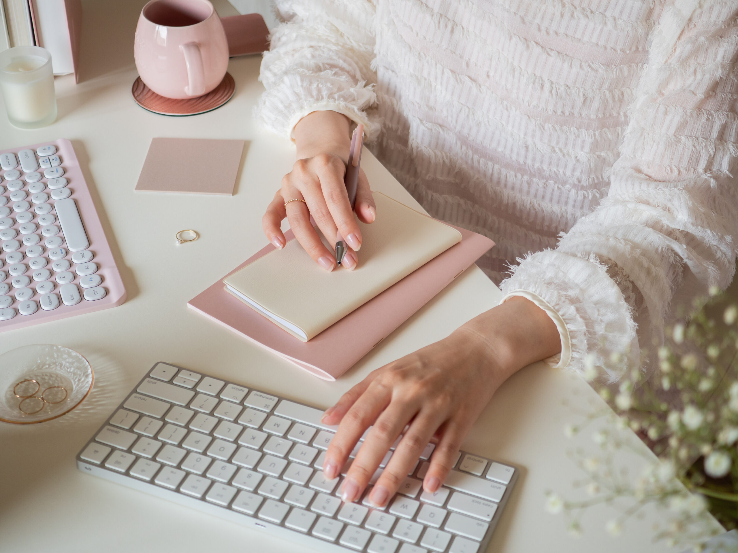 デスクでパソコンを使用しながらメモを取る女性の手元