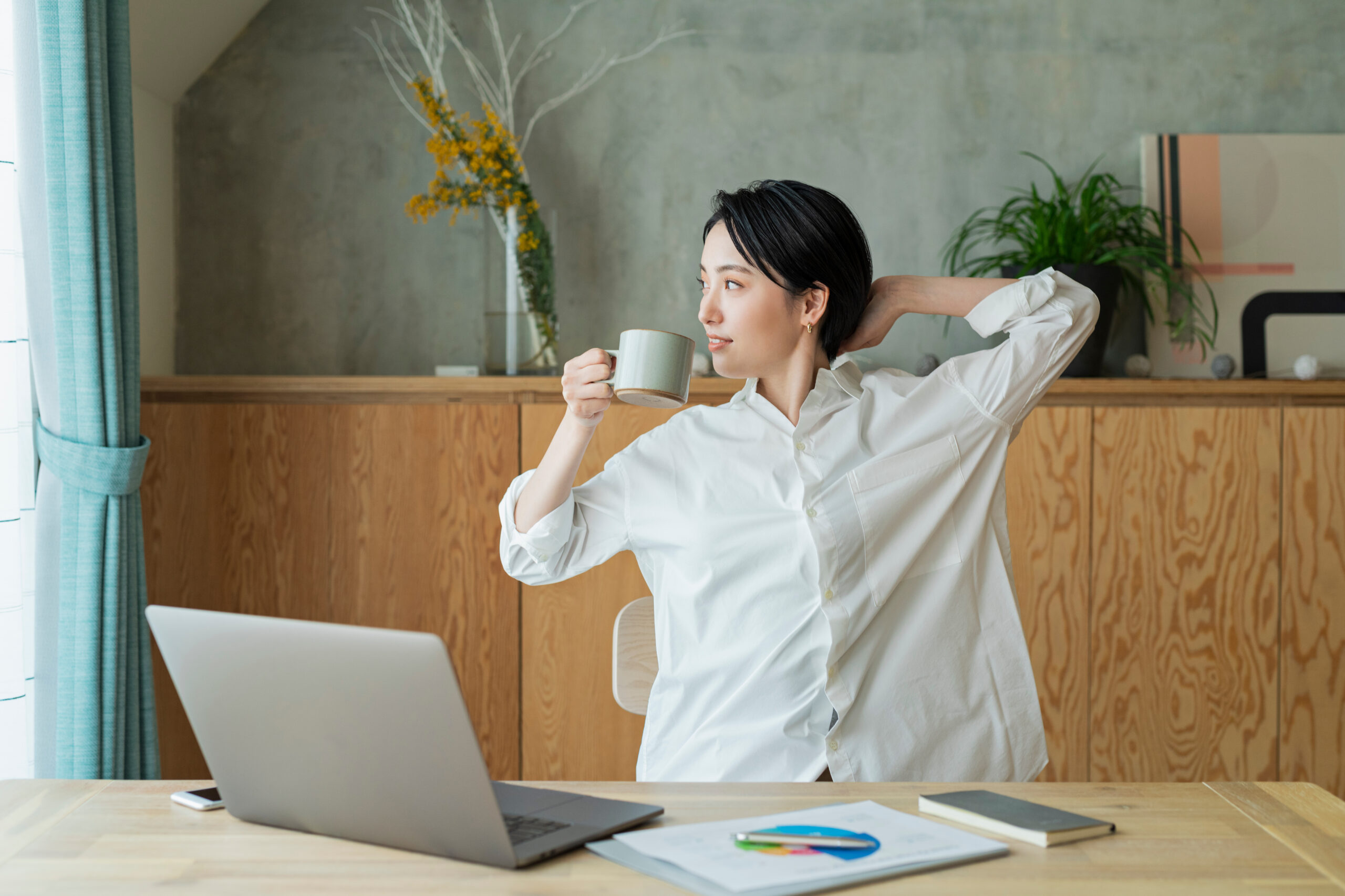 コーヒーを飲みながらリモートワークをする女性