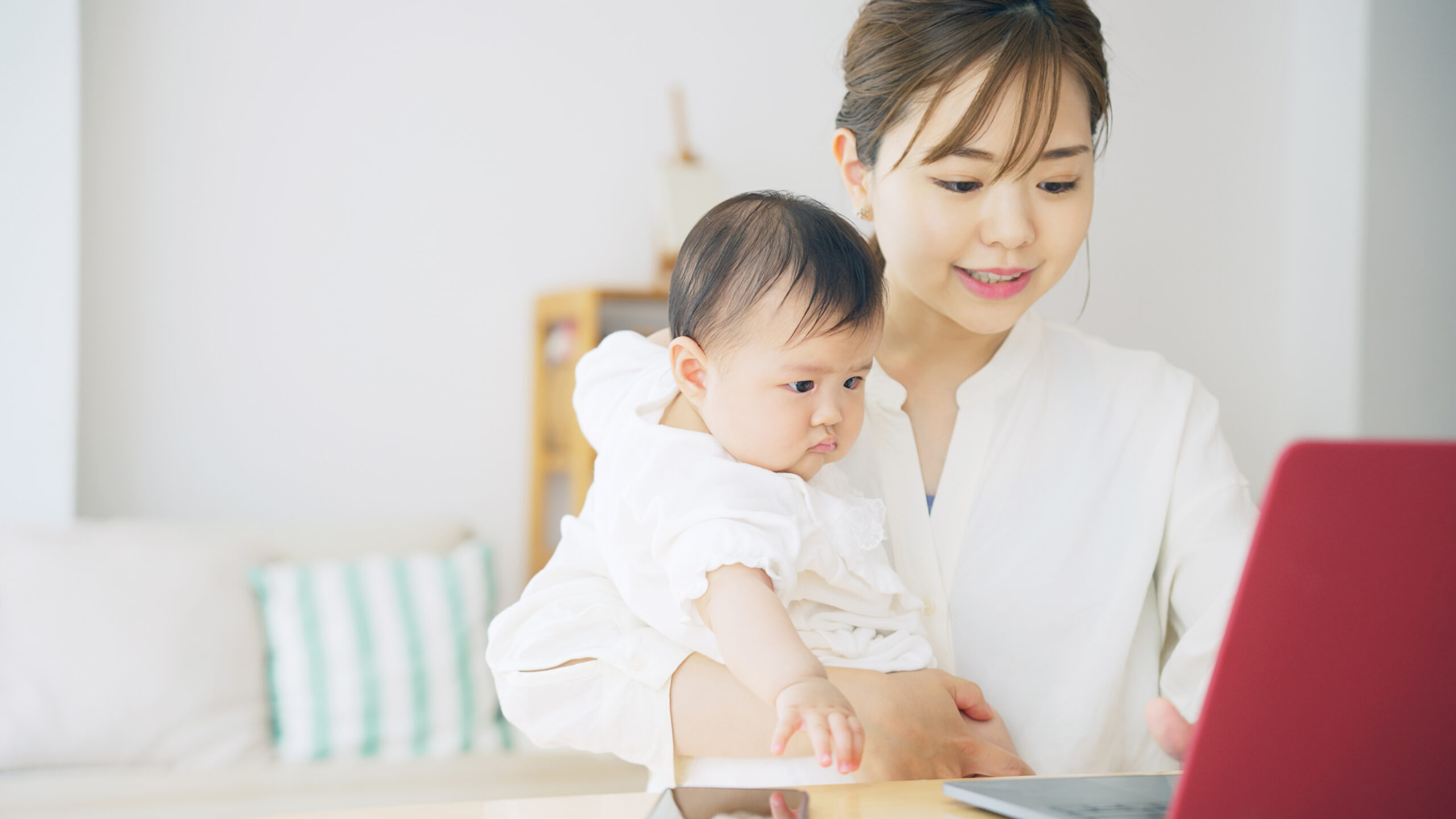 赤ちゃんを抱っこしながら自宅で仕事する女性